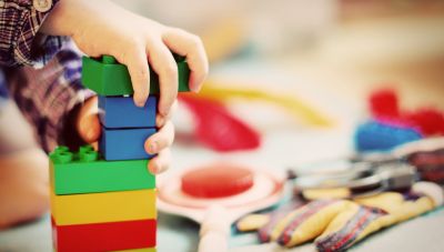 Kinderhände bauen einen Turm als bunten Bauklötzen